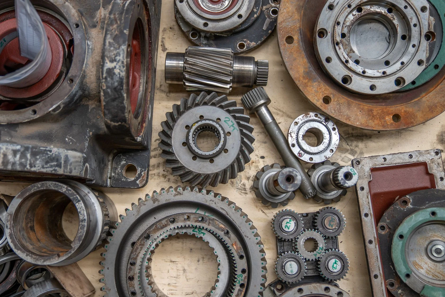 A disassembled gearbox laid out on a bench: helical gears, bearing races, housings and shafts, every one a line on somebody's bill of materials