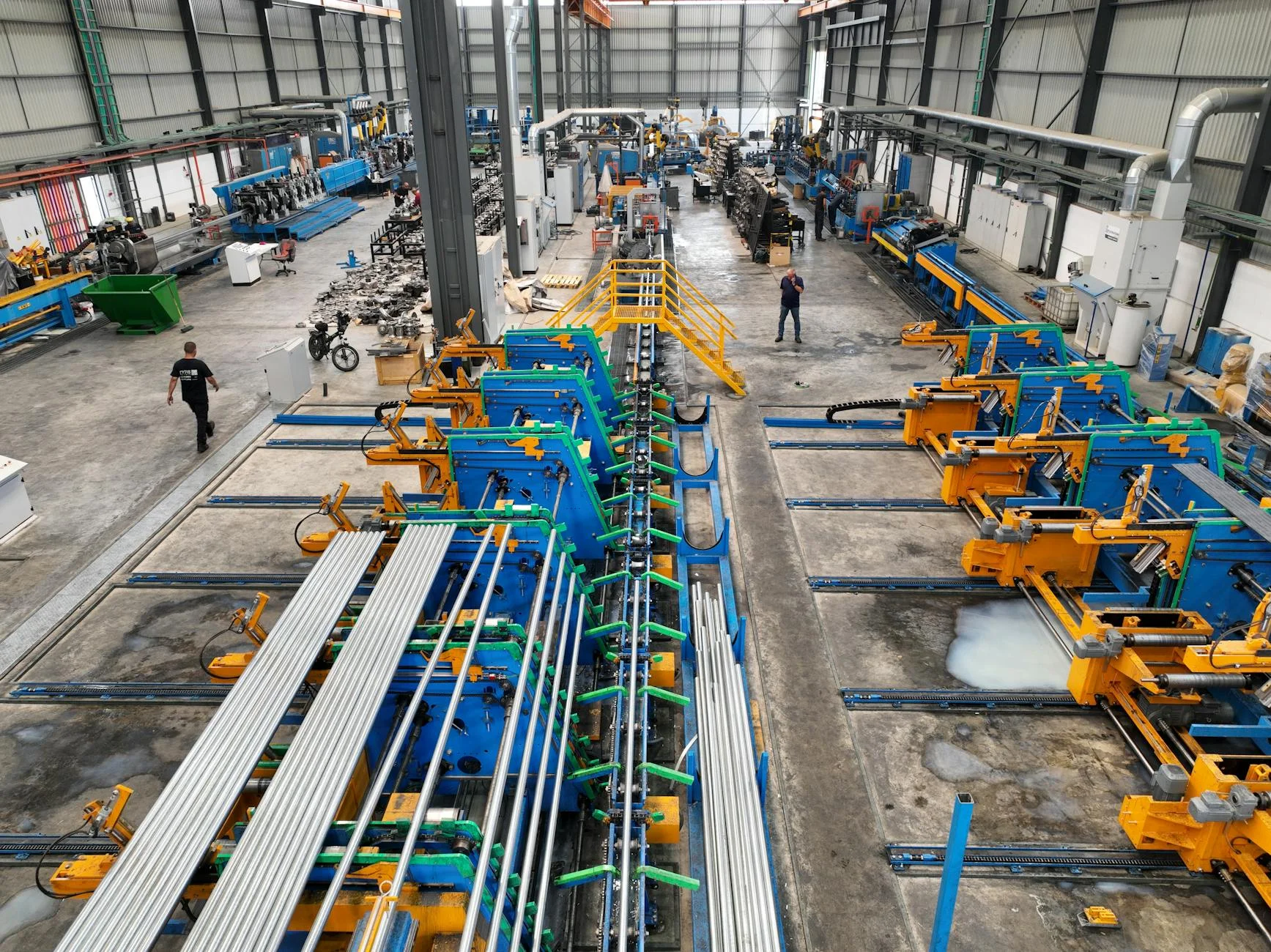 Aerial view of a large industrial manufacturing plant interior with machinery and workers — the scale of operations where every industrial revenue cycle is built.